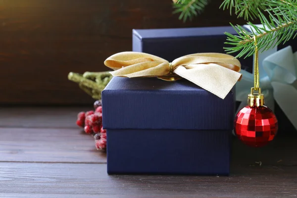 Cajas de regalo con cintas festivas y decoraciones navideñas sobre fondo de madera — Foto de Stock