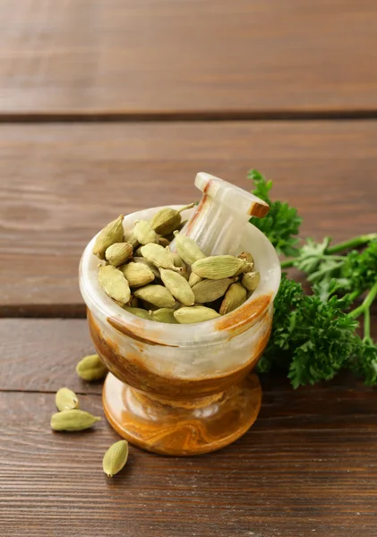 Cardamom in a stone mortar on a wooden table — Stock Photo, Image