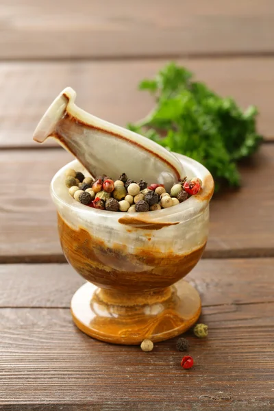 Peppercorns in a stone mortar on a wooden table — Stock Photo, Image