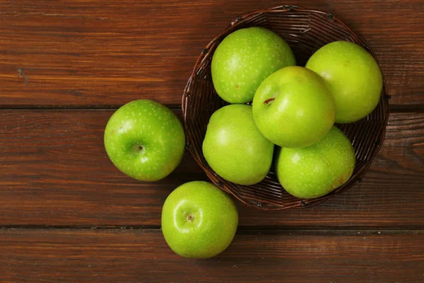 Pommes vertes bio fraîches dans un panier sur un fond en bois — Photo