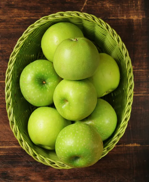Friss szerves zöld almát a kosárba a fából készült háttér — Stock Fotó