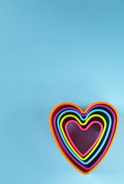 Coeurs en plastique colorés sur un fond bleu — Photo