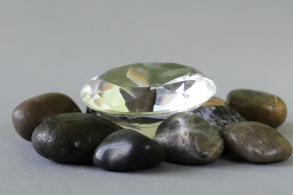 Grande diamante de vidro entre pedras cinzentas comuns — Fotografia de Stock