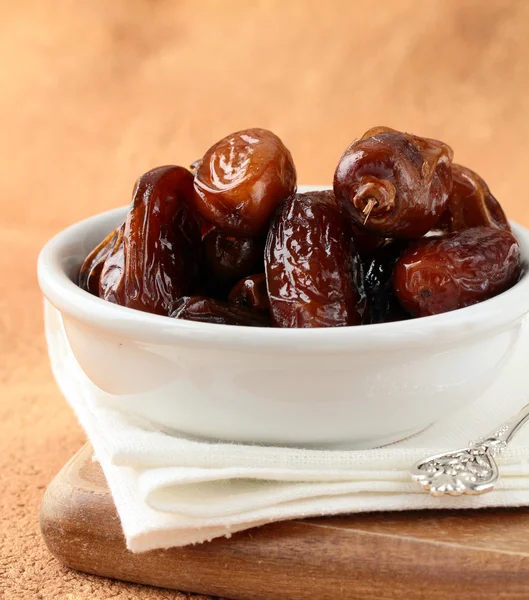 Los dátiles dulces secos en la escudilla a la mesa de madera — Foto de Stock