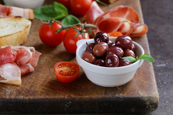 Comida italiana ainda vida - azeitonas, tomates, manjericão, presunto de prosciutto — Fotografia de Stock