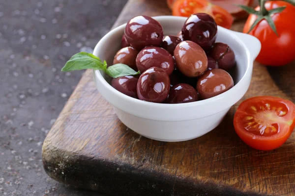 Italian food still life - olives, tomatoes, basil, prosciutto ham — Stock Photo, Image