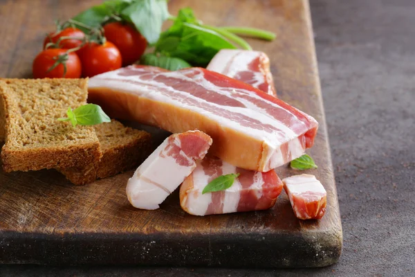 Bacon fumé au basilic et tomates sur une planche à découper — Photo