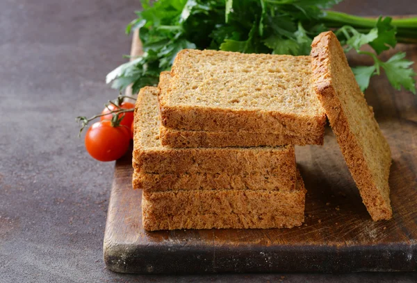 Rostat bröd med grönsaker och örter på en planka — Stockfoto