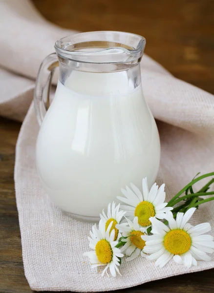 La brocca di latte su una tavola di legno desidera margherita, la natura morta rustica — Foto Stock