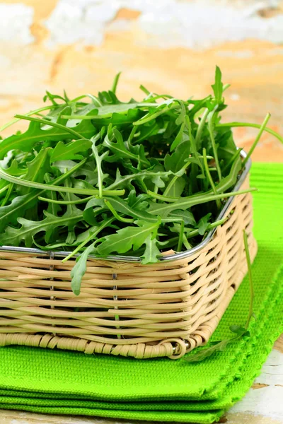 Fresh organic green arugula in a wicker basket — Stock Photo, Image