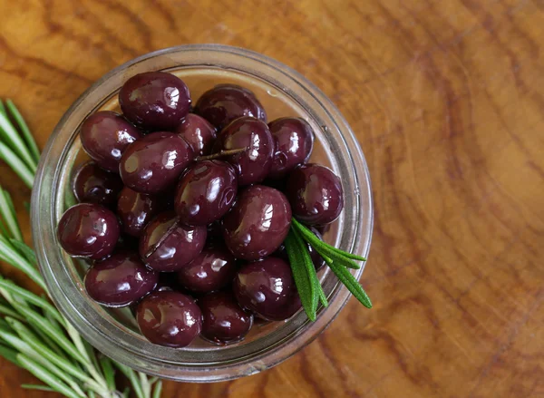 Olive nere naturali (rosse) con ramoscelli di rosmarino fresco — Foto Stock