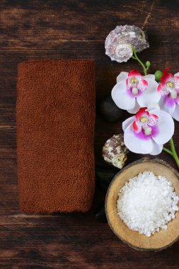 Spa konsept - havlu, tuz ve ahşap arka plan üzerinde orkide