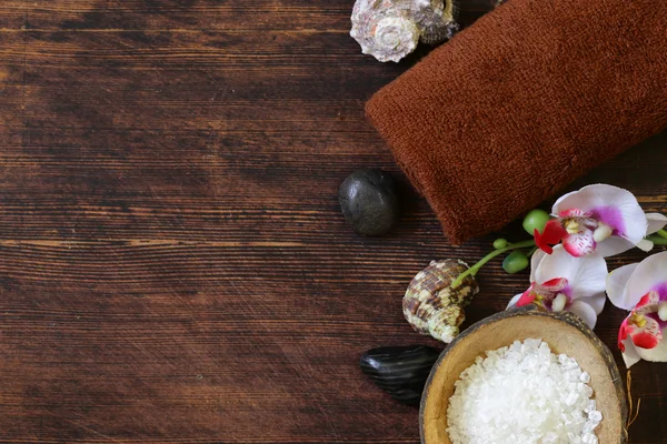 Spa konsept - havlu, tuz ve ahşap arka plan üzerinde orkide