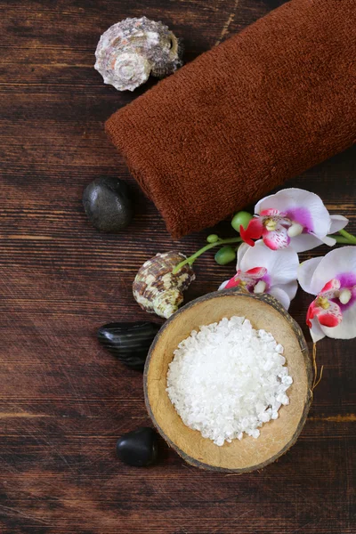 СПА-концепция - полотенце, соль и орхидея на деревянном фоне — стоковое фото