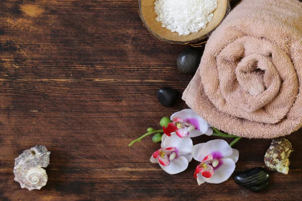 Spa koncept - ręcznik, soli i orchidea na drewniane tła — Zdjęcie stockowe