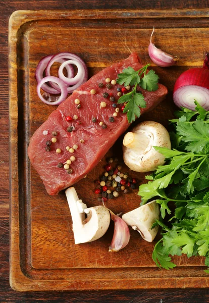 Fresh raw beef meat on a cutting board with vegetables and spices — Stock Photo, Image