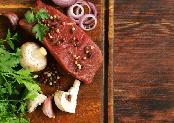 Carne fresca de res cruda en una tabla de cortar con verduras y especias —  Fotos de Stock