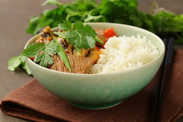 Traditional Asian food - white rice and meat with vegetables in soy sauce
