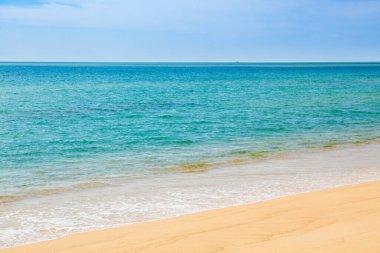 Mavi gökyüzü, dalga ve kumsal arka planının güzelliği.