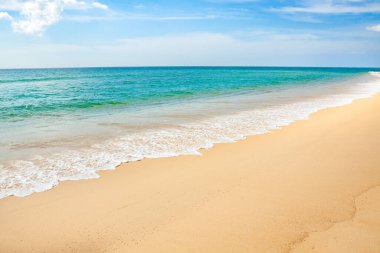 Mavi gökyüzü, dalga ve kumsal arka planının güzelliği.