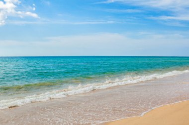 Mavi gökyüzü, dalga ve kumsal arka planının güzelliği.