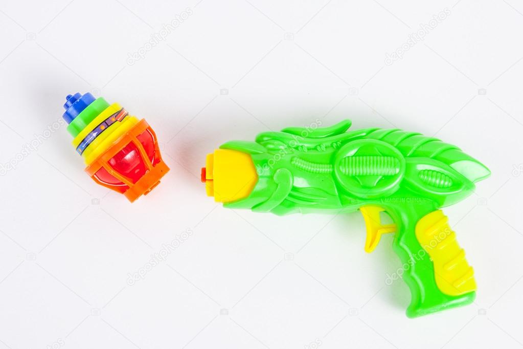 toy gun with spinning top on white paper background 