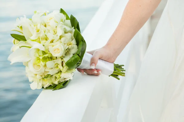 Noiva está segurando um buquê de casamento — Fotografia de Stock