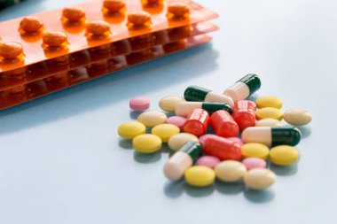 Haplı paketler, renkli haplar ve mavi arka planda kapsüller. Sigorta tıbbı kavramı, yüksek maliyetli ilaçlar. Sağlık ve İlaç Hizmetleri.