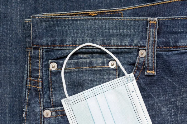 青いジーンズのポケットには保護面が横たわっています Covid 19コロナウイルスパンデミック後の新しいライフスタイルのコンセプト — ストック写真