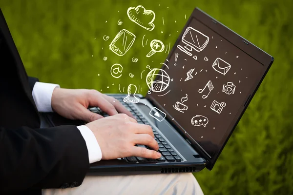 Hand writing on notebook computer with media icons — Stock Photo, Image