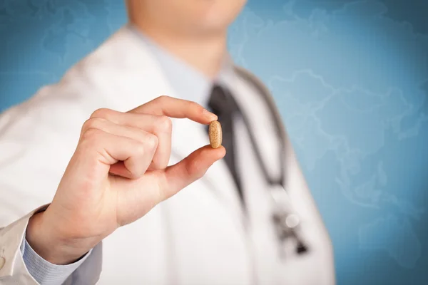 Doctor en blanco sosteniendo una píldora — Foto de Stock