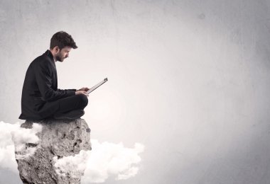 Ofis çalışanı kayanın tepesinde oturuyor.