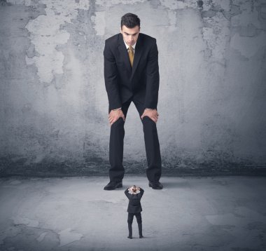 Büyük işletme zorbası küçük iş arkadaşına bakıyor.