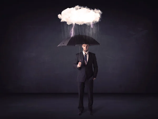 Empresario de pie con paraguas y pequeña nube de tormenta — Foto de Stock