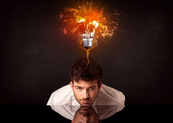 Businessman sitting under a blowing idea bulb — Stock Photo, Image