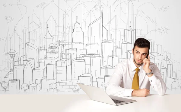 Empresário sentado à mesa branca com edifícios desenhados à mão — Fotografia de Stock