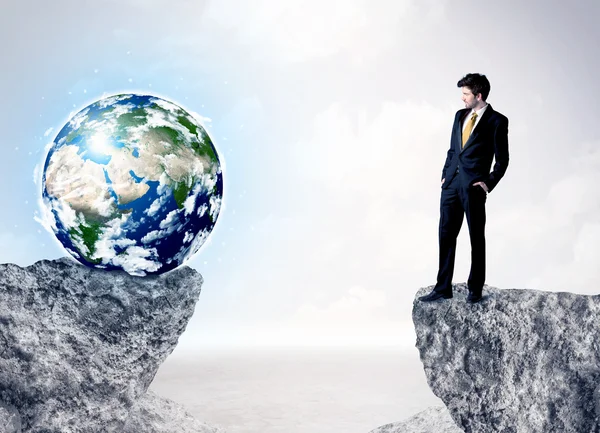 Businessman on rock mountain with a globe — Stock Photo, Image