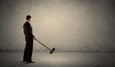 Pis bir duvarın önünde elinde çekiçle duran bir iş adamı.