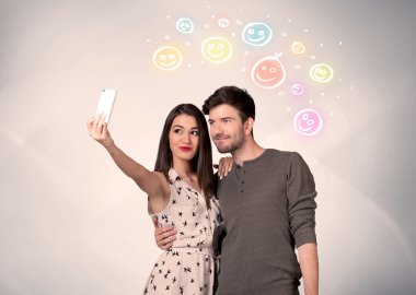 Mutlu çift gülen yüzle selfie çekiyor.