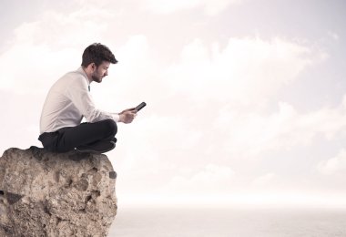 İş adamı taşın üstünde oturuyor.