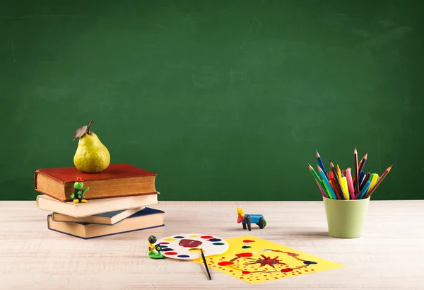 Schoolspullen op bureau met leeg schoolbord — Stockfoto