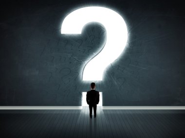 Parlak bir soru işaretiyle duvara bakan bir iş adamı 