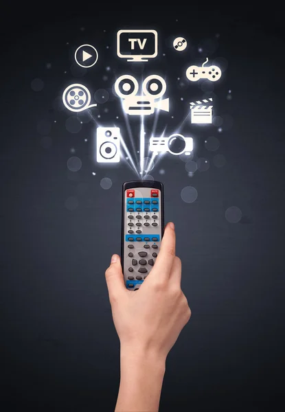 Tangan dengan remote control dan ikon media — Stok Foto