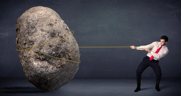 Businessman pulling huge rock with a rope — Stock Photo, Image