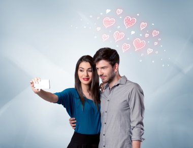Aşık çift kırmızı kalple selfie çekiyor.
