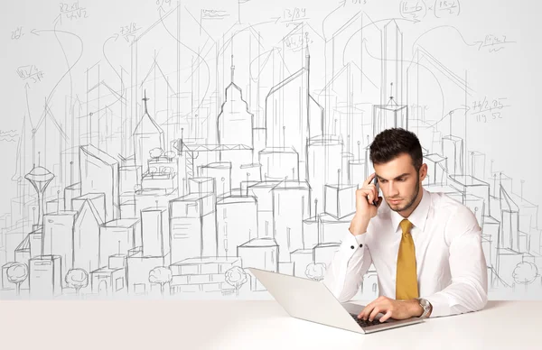 Empresário sentado à mesa branca com edifícios desenhados à mão — Fotografia de Stock