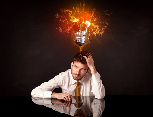Podnikatel sedí pod foukající nápad žárovka — Stock fotografie