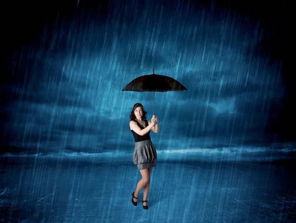 Business woman standing in rain with an umbrella — Stock Photo, Image