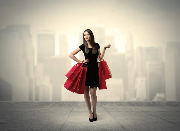 Elegante chica de ciudad con bolsas de compras rojas —  Fotos de Stock