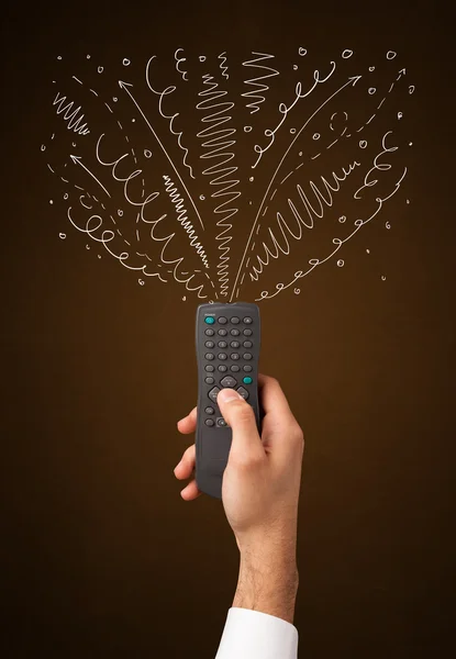 Hand with remote control and curly lines — Stock Photo, Image